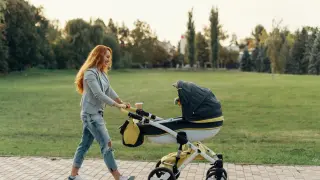 Radosny pierwszy spacer z noworodkiem w wózku po parku.
