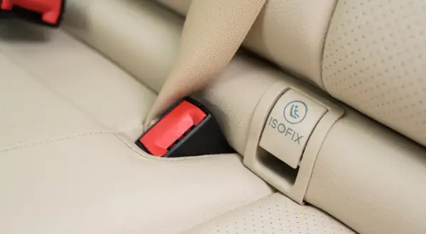 Widoczny symbol ISOFIX na jasnej tapicerce fotela samochodowego to klucz do bezpiecznego montażu fotelika.